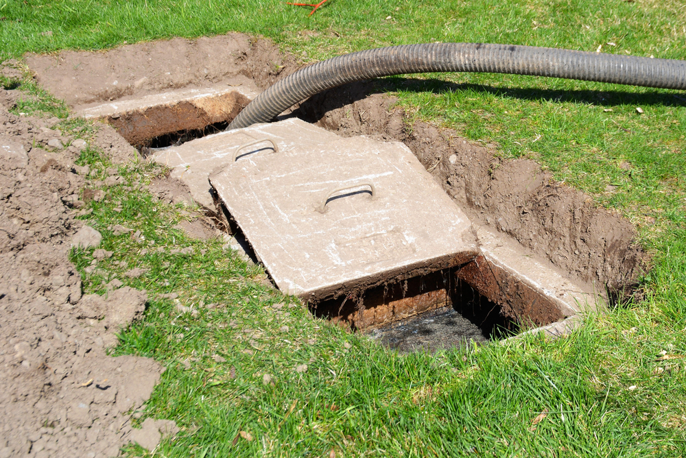 A worker doing routine maintenance pumping out a home septic tank